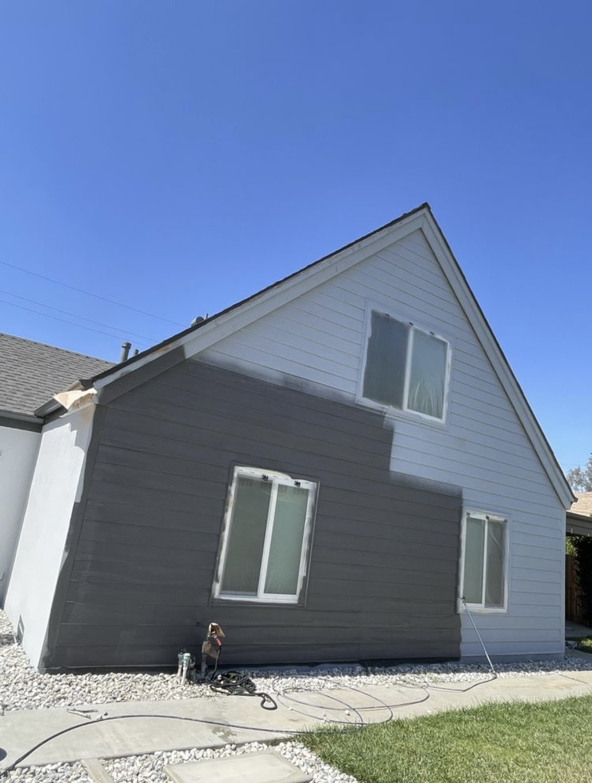 Gable siding mid-repaint, dark gray coat going over white siding