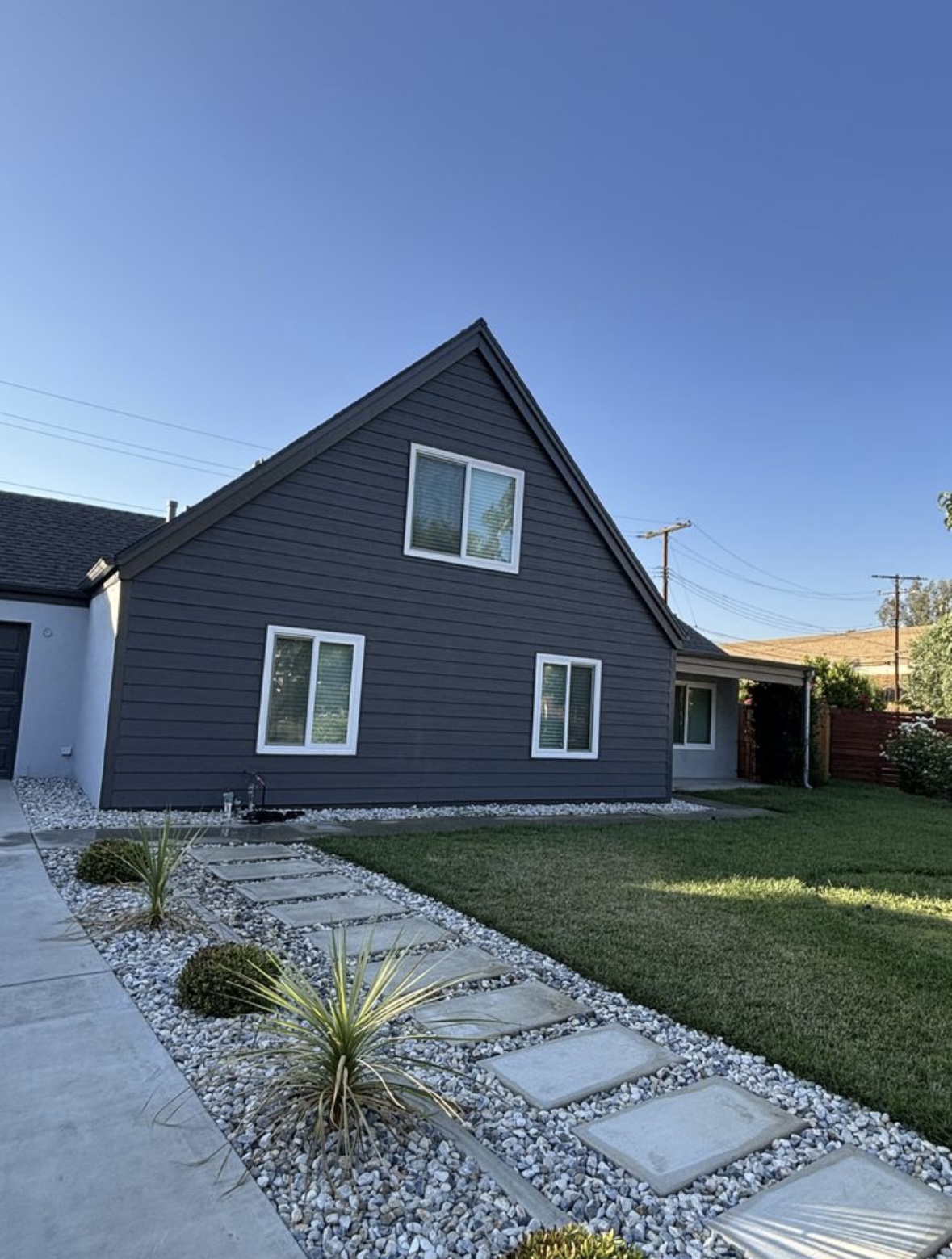 Home exterior repainted charcoal gray with crisp white window trim